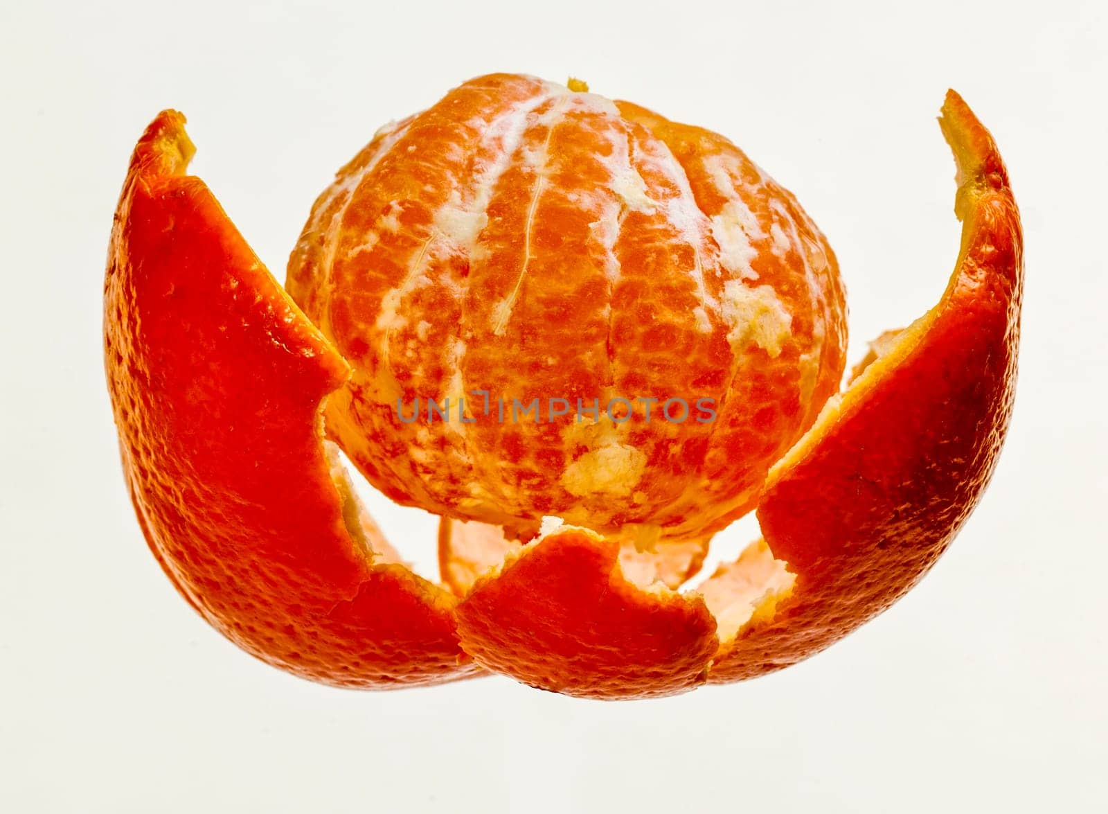 Lovely fresh juicy peeled tangerine with segments lose inside the peel, isolated on white