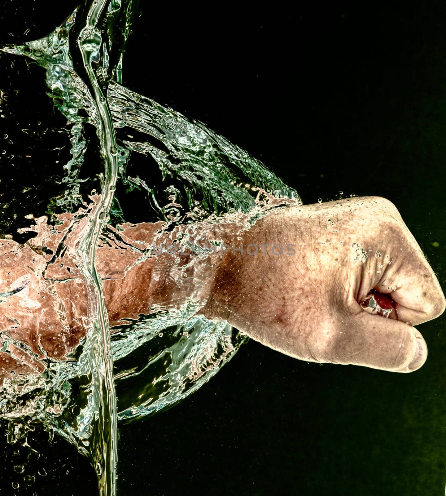 Punching Through Water  - Close-up of a man s fist punching through water horizontally, display of movement and force against black.