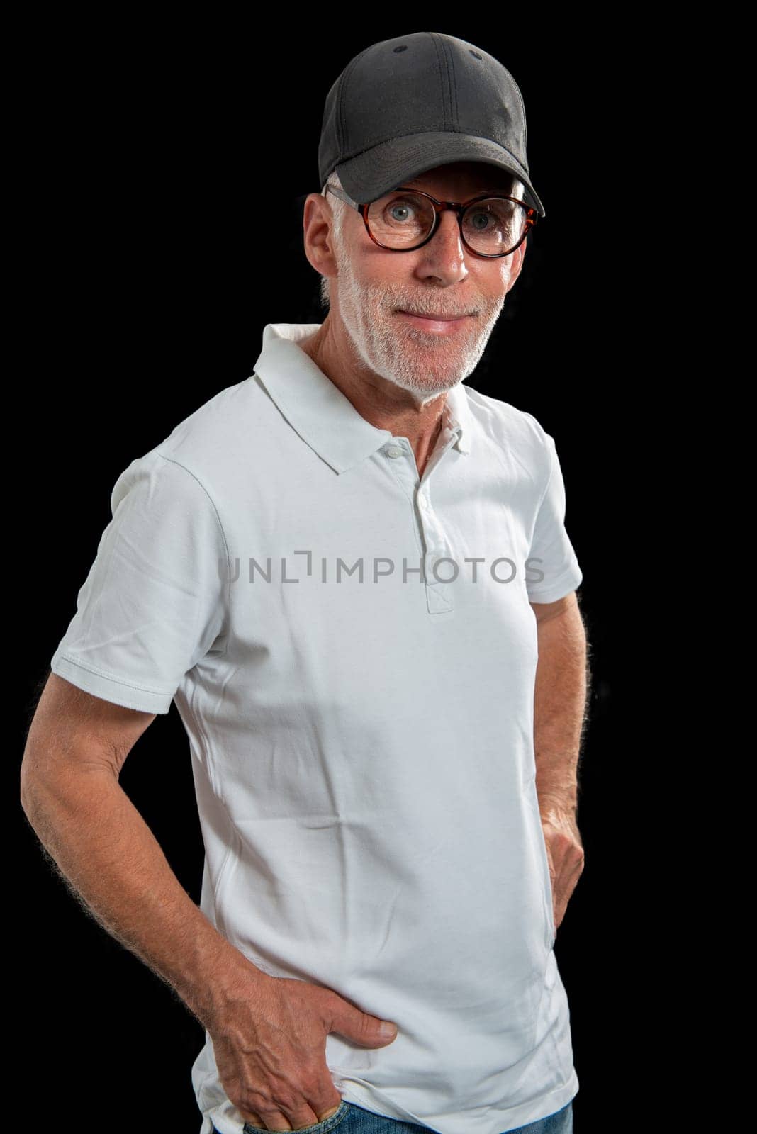 a sixty year old man wearing a baseball cap on black background