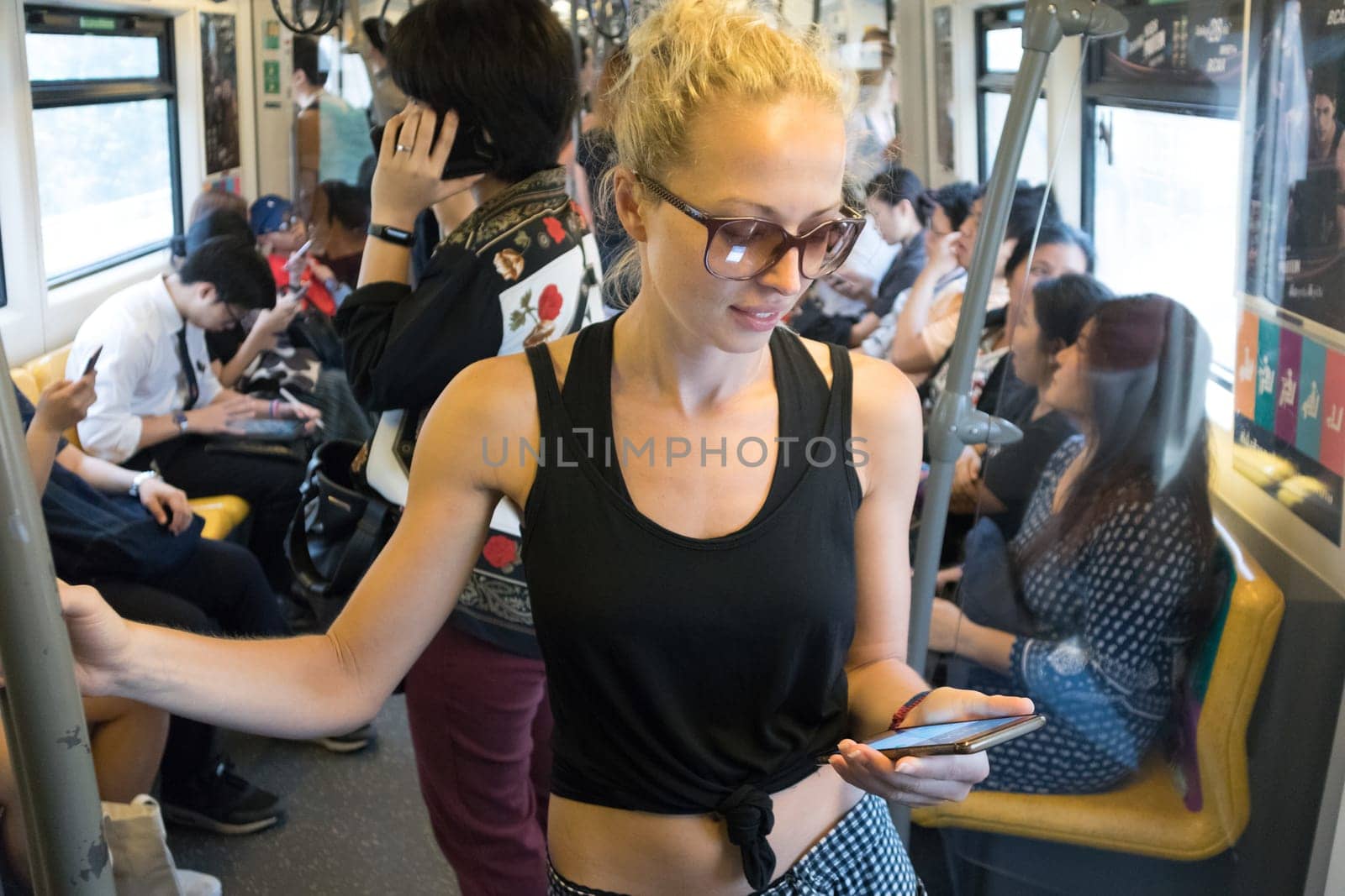 Caucasian female traveler using mobile phone on public transport metro in Kuala Lumpur,capital of Malaysia.