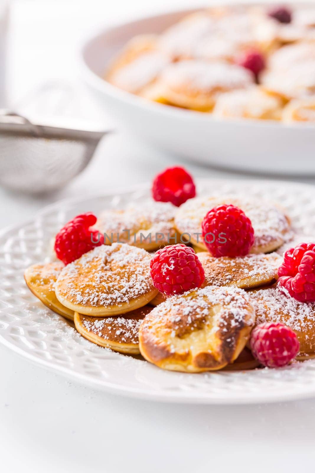 Poffertjes - small Dutch pancakes with fresh raspberries. Traditional Dutch cuisine.