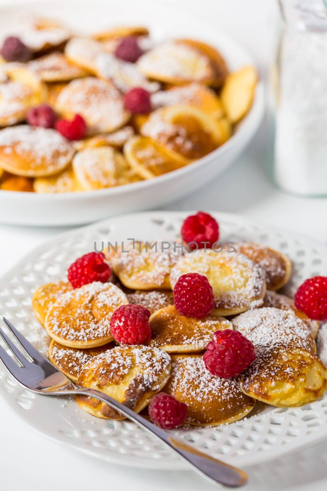 Poffertjes - small Dutch pancakes with fresh raspberries. Traditional Dutch cuisine.