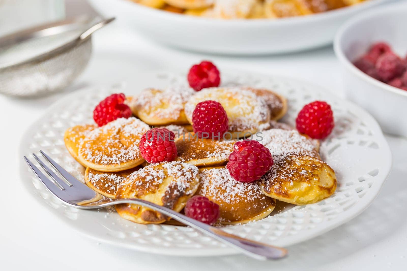 Poffertjes - small Dutch pancakes with fresh raspberries. Traditional Dutch cuisine.