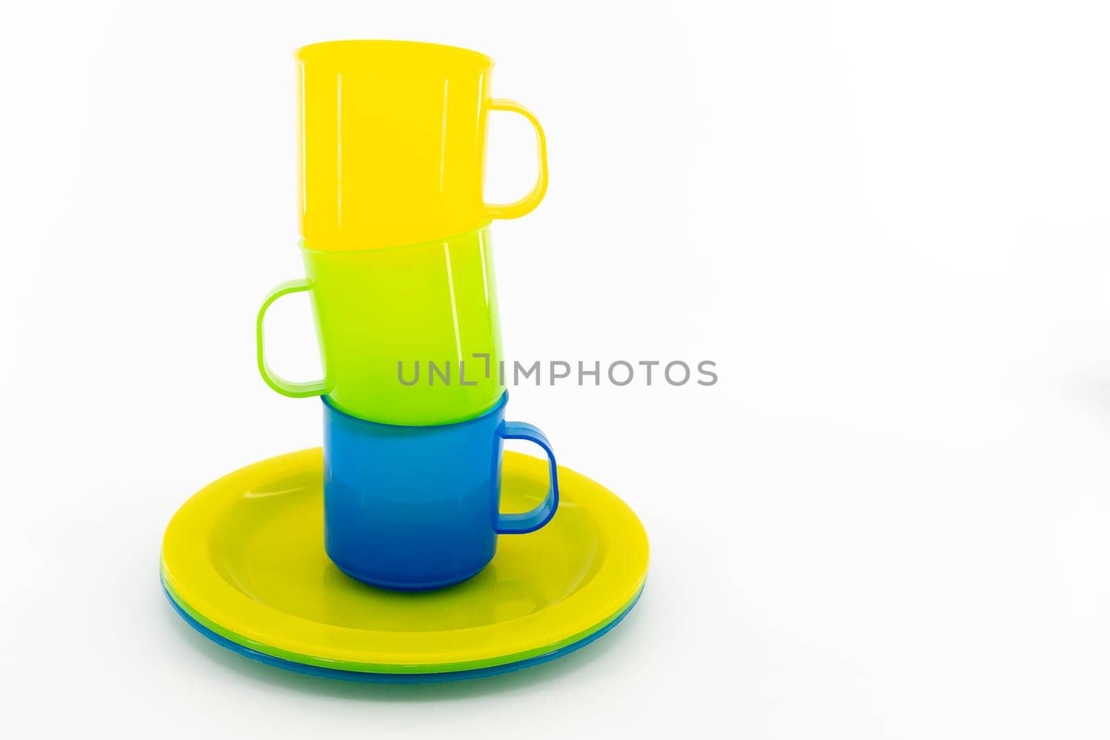 The three colored mugs and three colored saucers on a white background