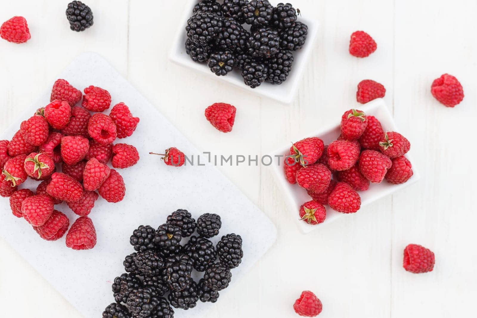 raspberries and blackberries white wooden background.