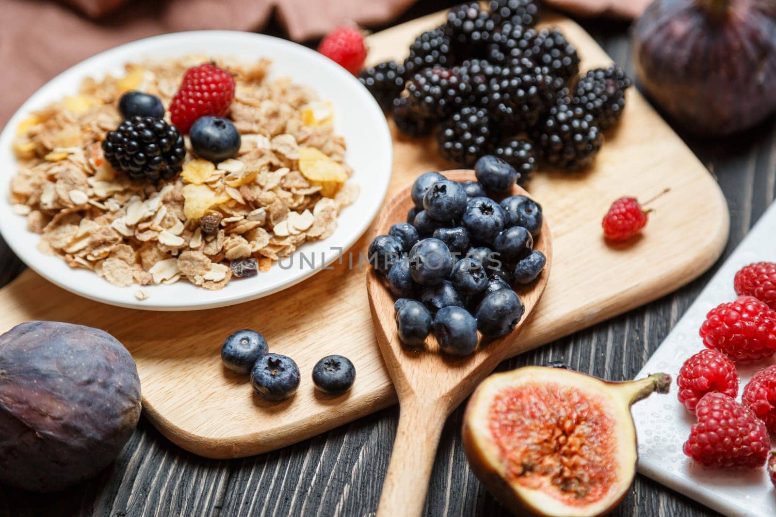 Healthy breakfast set. Muesli and berries on dark rustic background.