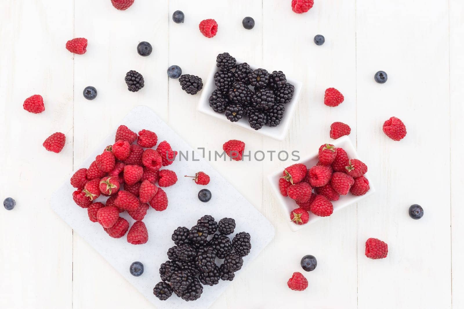 Blueberries, raspberries and blackberries on white background.