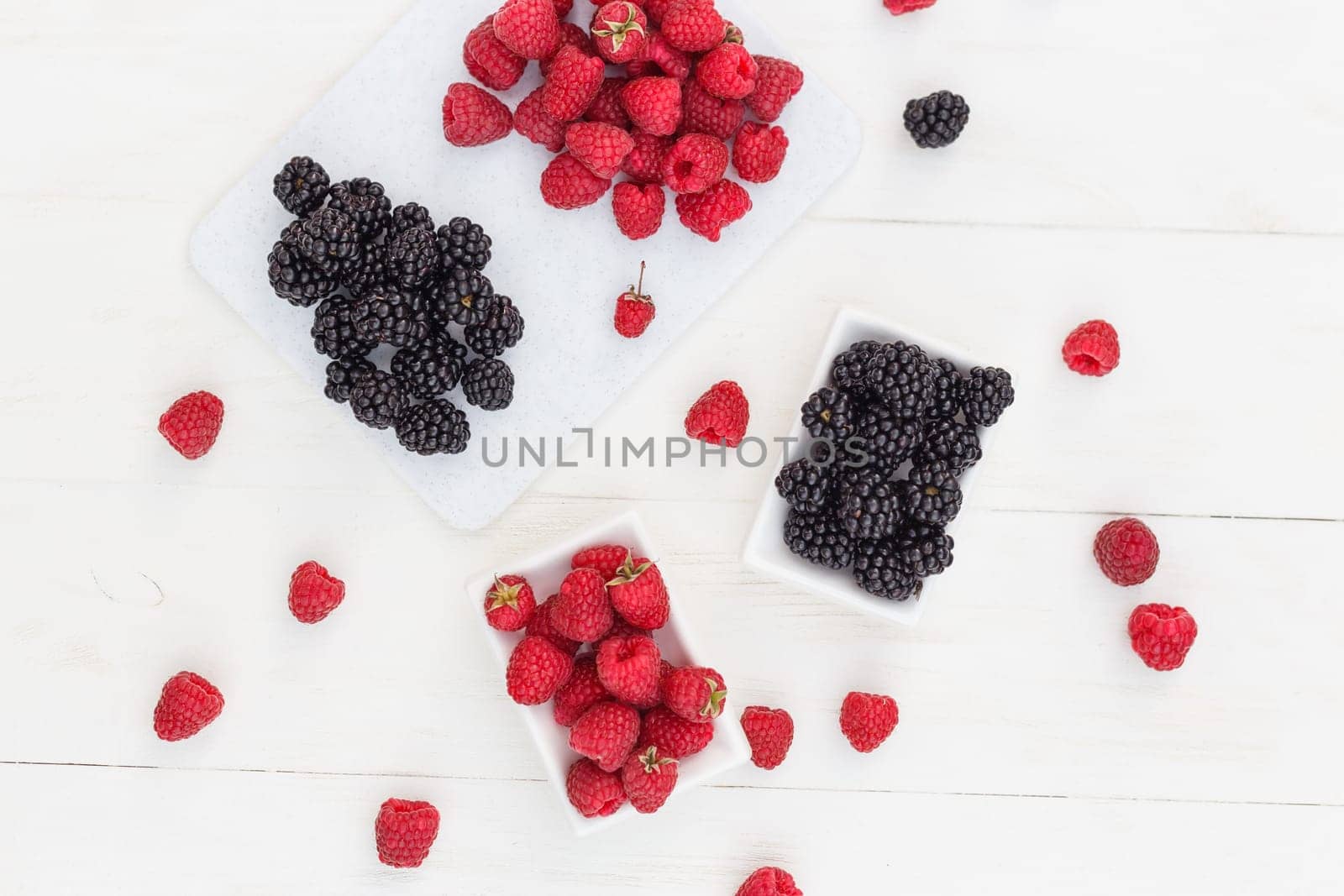 raspberries and blackberries white wooden background.