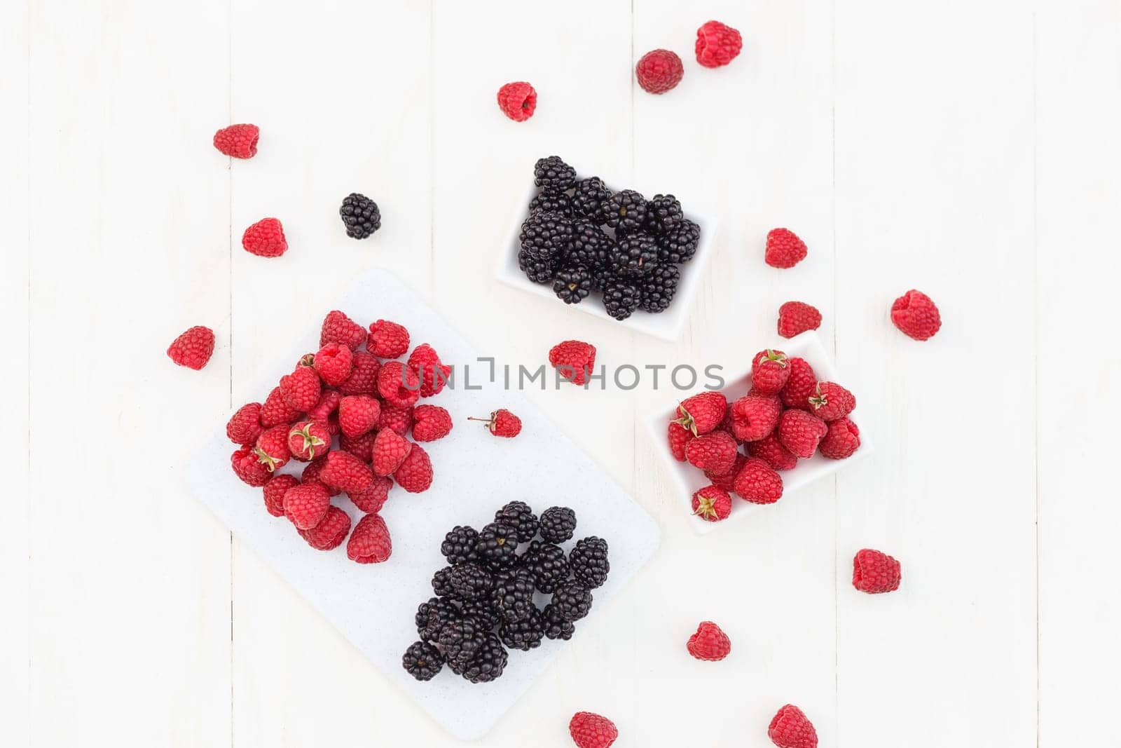 raspberries and blackberries white wooden background.