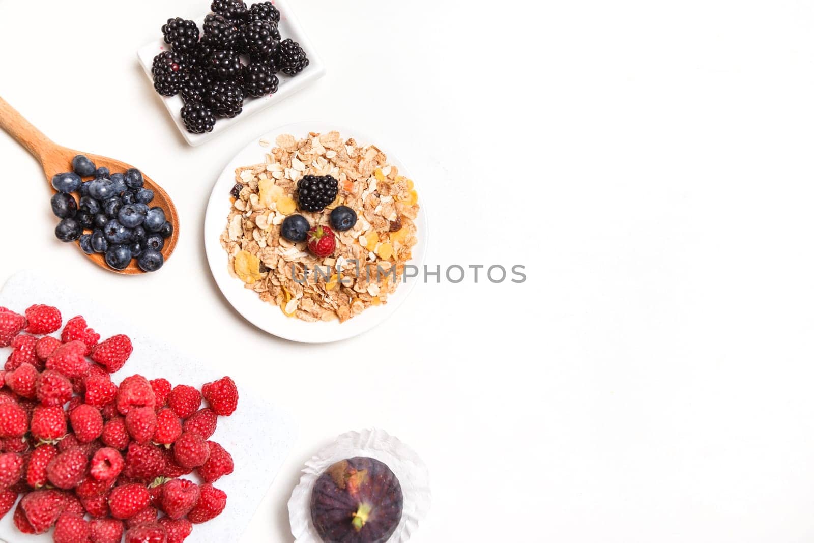 bowl of corn flakes with berries on white background