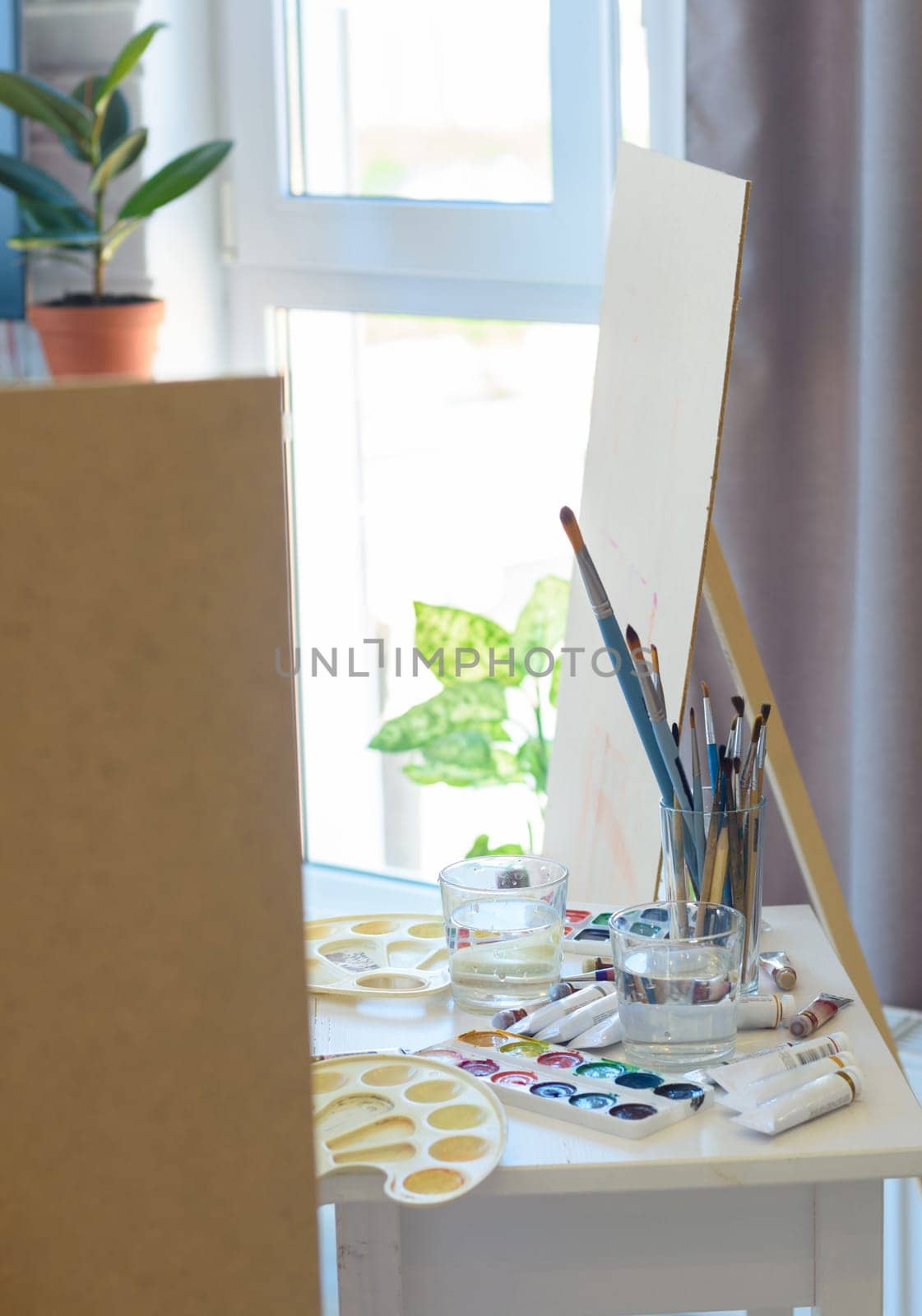 artist's workplace with easel, brushes and paints
