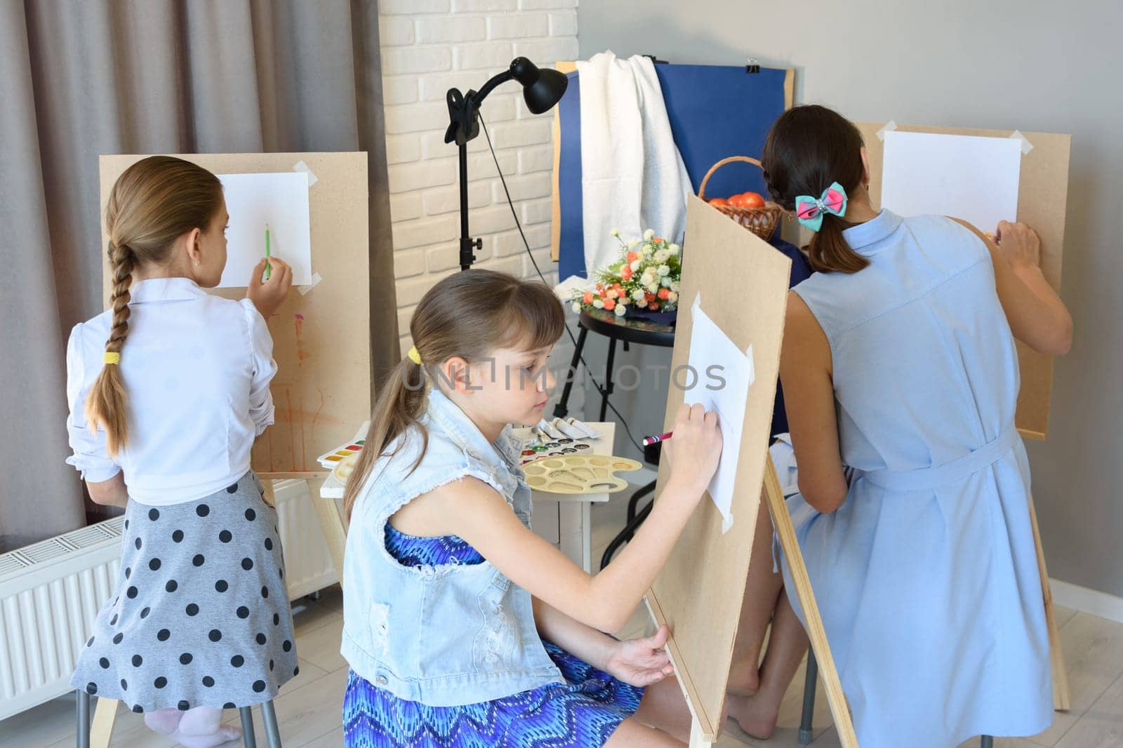 classes in the art studio behind the easels of children and adults