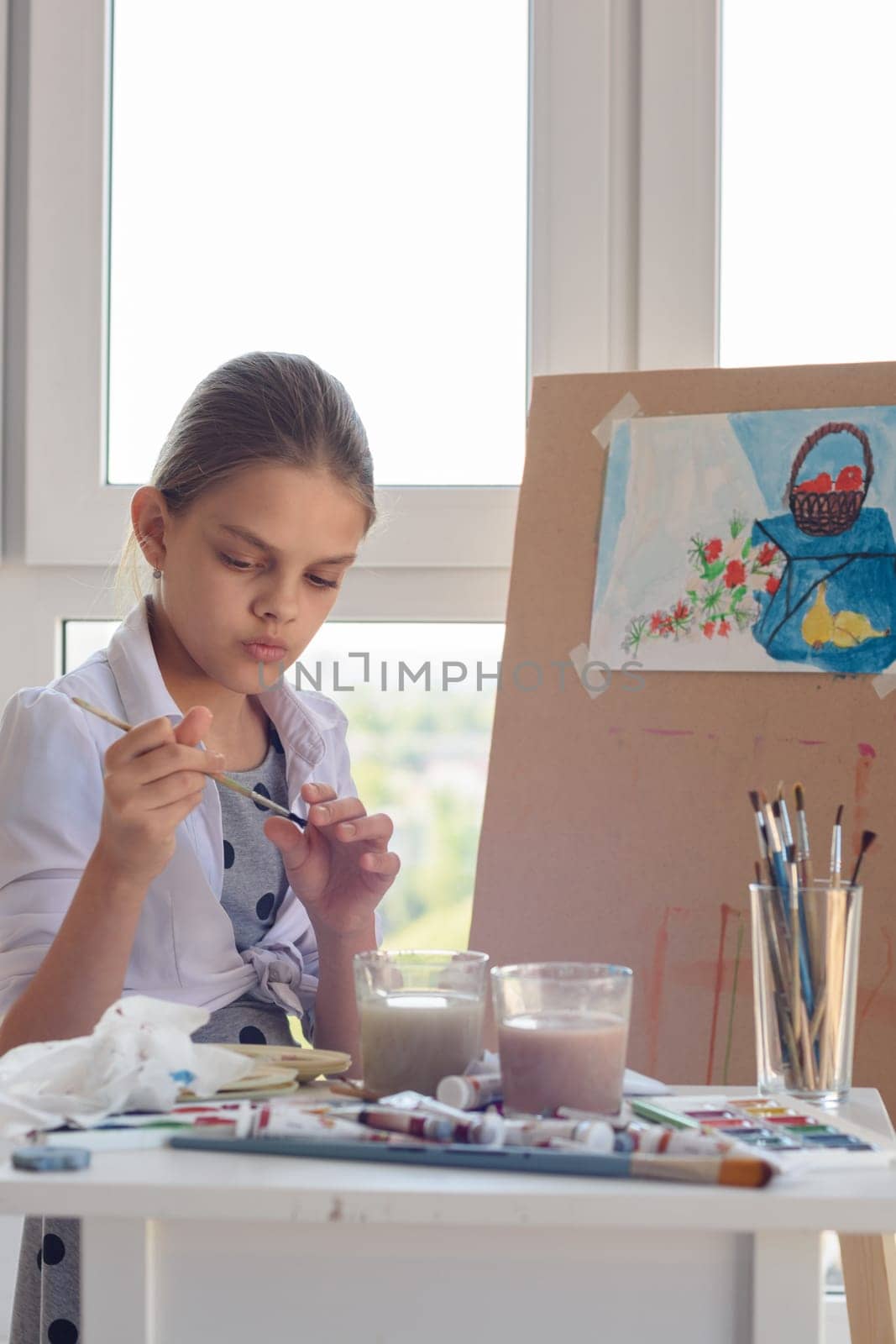Girl examines brush for drawing watercolor paints