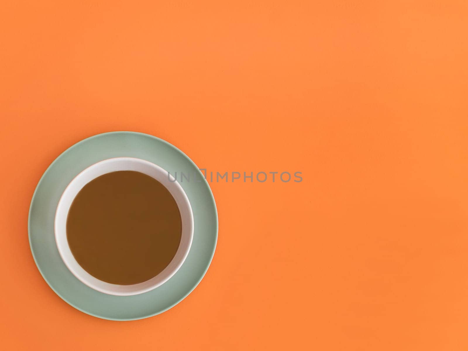 Chocolate bowl on a green light plate. Orange background. Copy space.