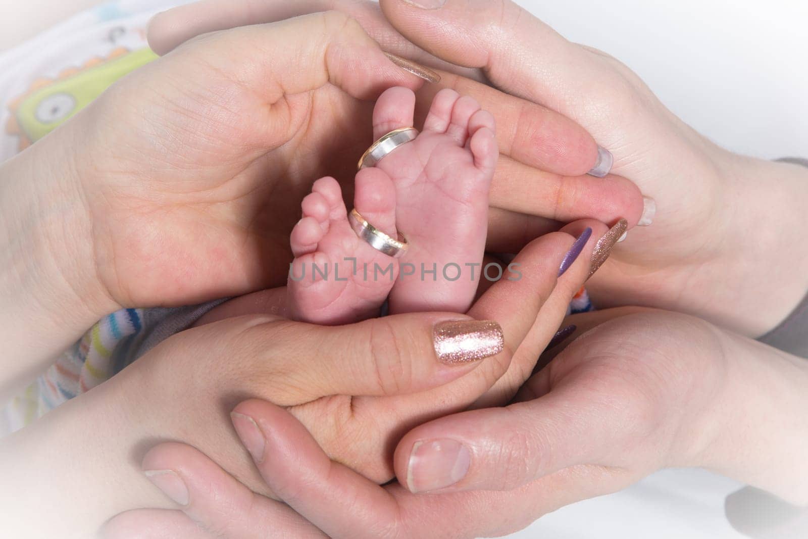 The Hands of adults hold small baby feet