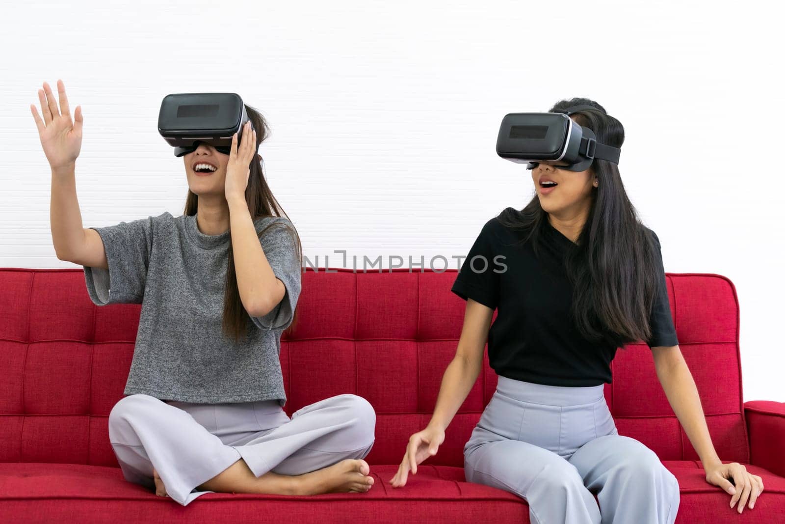 Two Asian beautiful women smiling during playing VR video games experience in living room house for good mental health while quarantine. Game technology leisure and mental health concept.