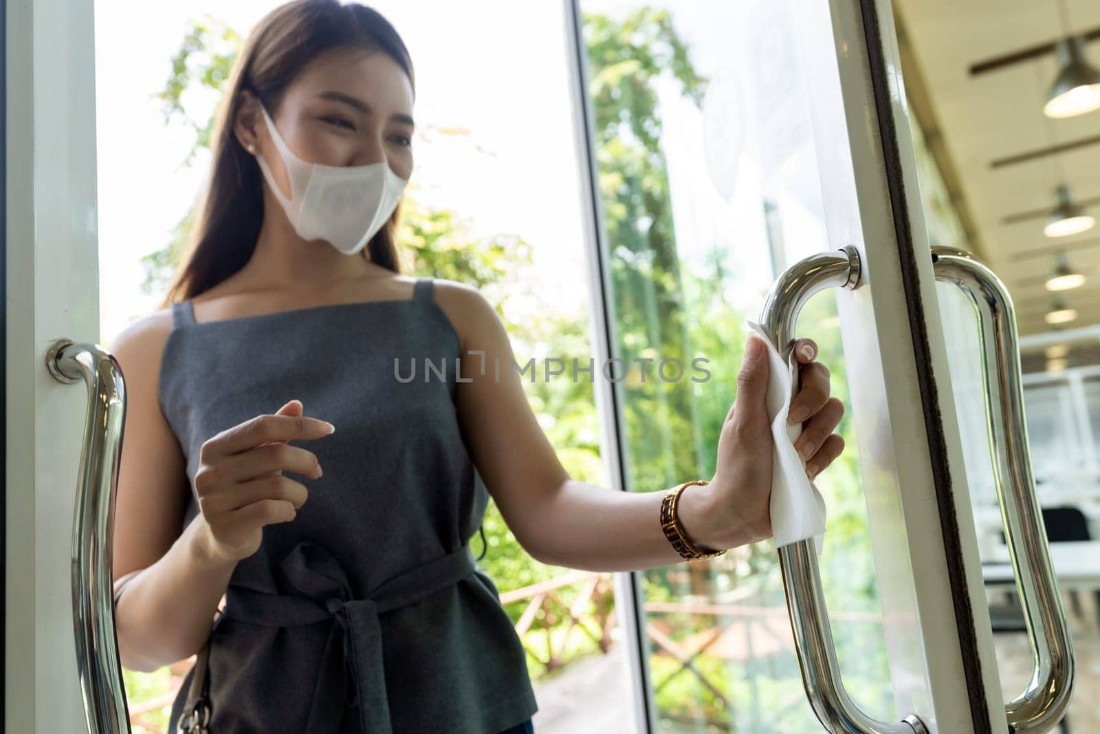 close up of asian woman hand with tissue paper to push restaurant door open reduce hand touching on public place to reduce chance to infection by coronavirus covid-19. New normal lifestyle concept