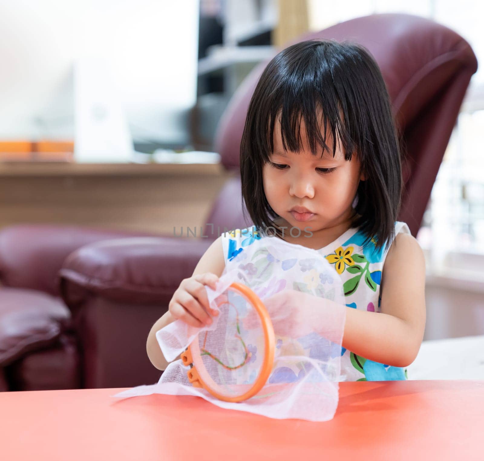 Asian girl child sewing in living room at home as home schooling while city lockdown because of covid-19 pandemic across the world. Home Scholling prepare for Preschool concept.