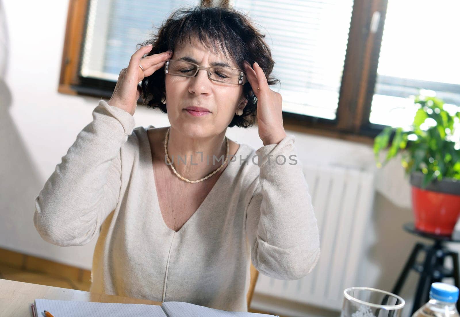 a mature brunette woman in the office has a headache and closes her eyes