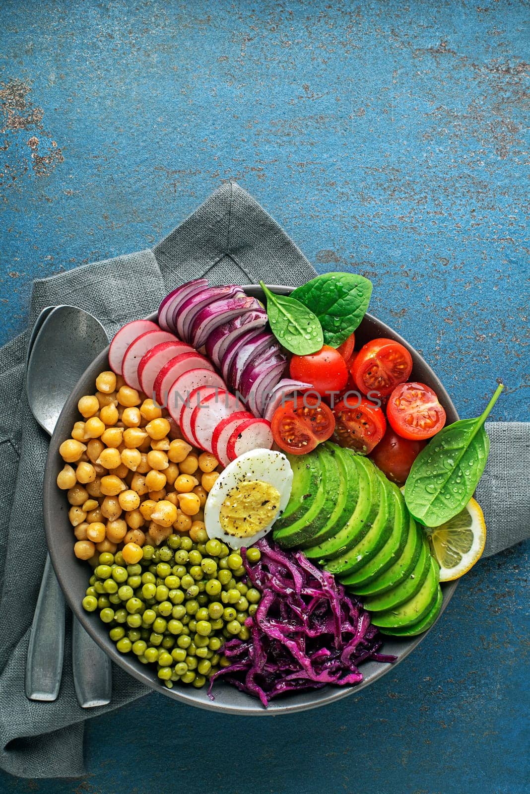 Healthy vegan lunch bowl. Vegetable dishes with Avocado, chickpeas, tomato, red cabbage, green peas, red onion and egg