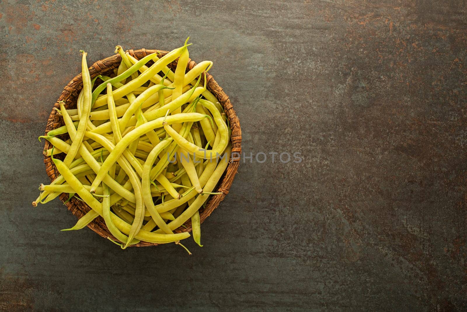 Fresh picked yellow wax beans in to basket on dark background