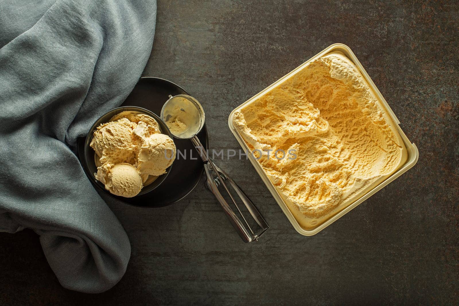 Fresh of vanilla ice cream scoops, scooped out of container in to bowl with a silver utensil