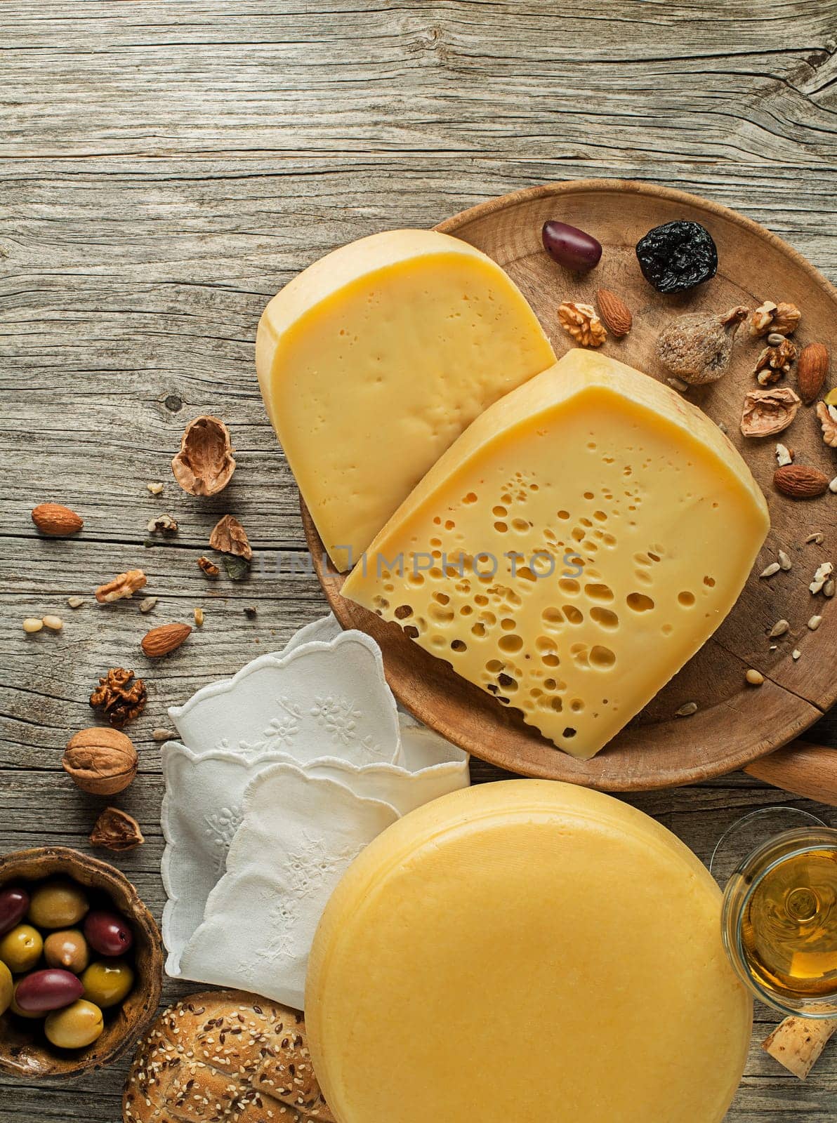 Assortment of cheeses, wine, nuts and fruits on a wooden table. Top view. Free space for text.