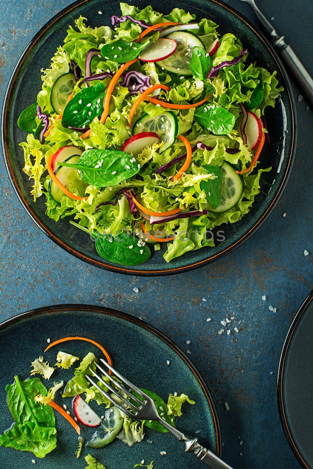 Green lettuce salad meal with fresh mixed vegetables on blue table background