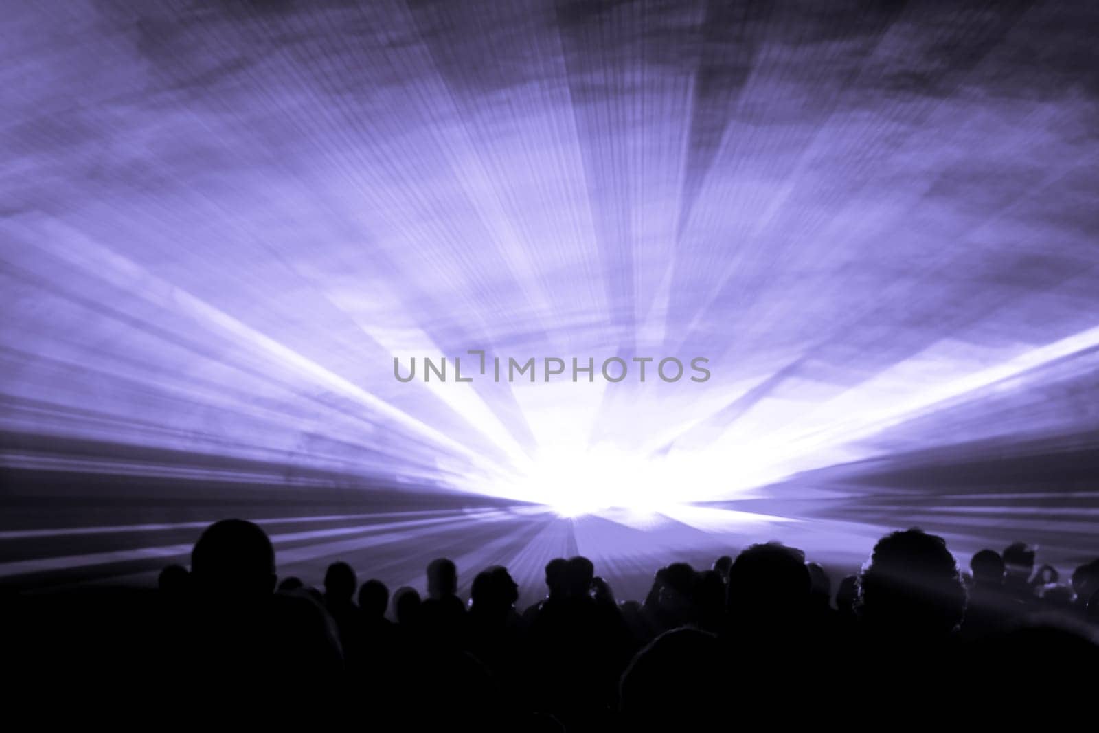 Luxury entertainment with audience silhouettes in nightclub event, festival or New Years Eve. Beams and rays shining colorful lights.