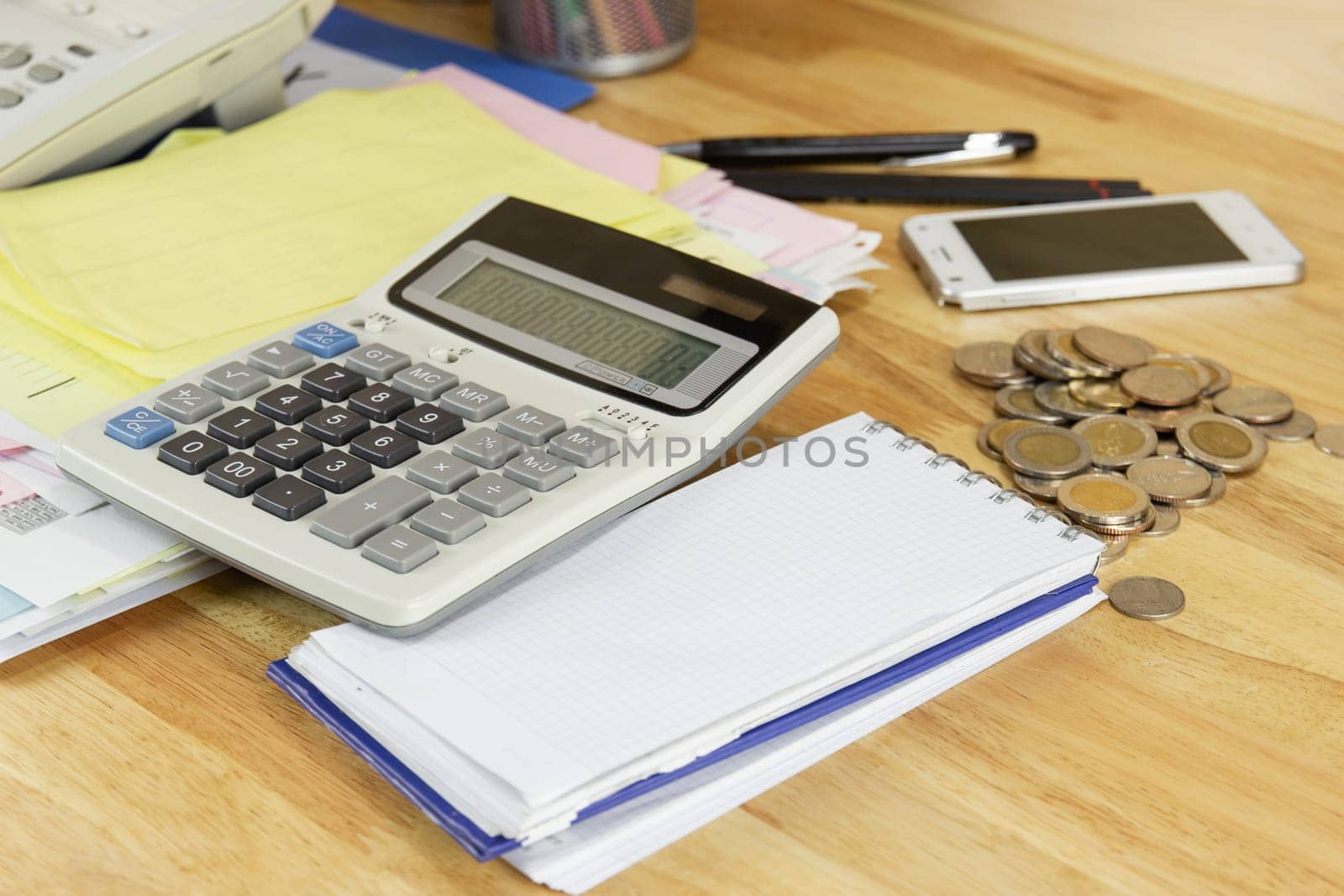 the calculator with coin on wood table at office, concept of calculating expenses, incomes and expenses.