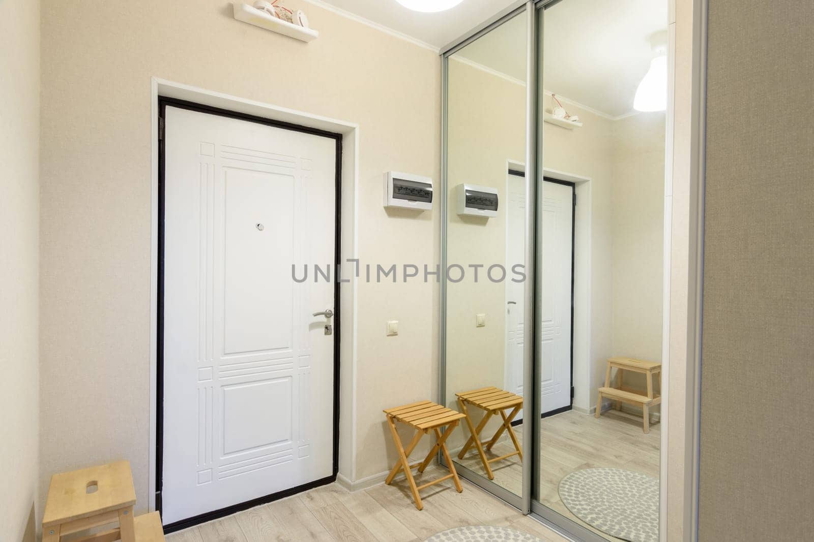 Entrance hall interior with metal front door and large sliding wardrobe with mirrors
