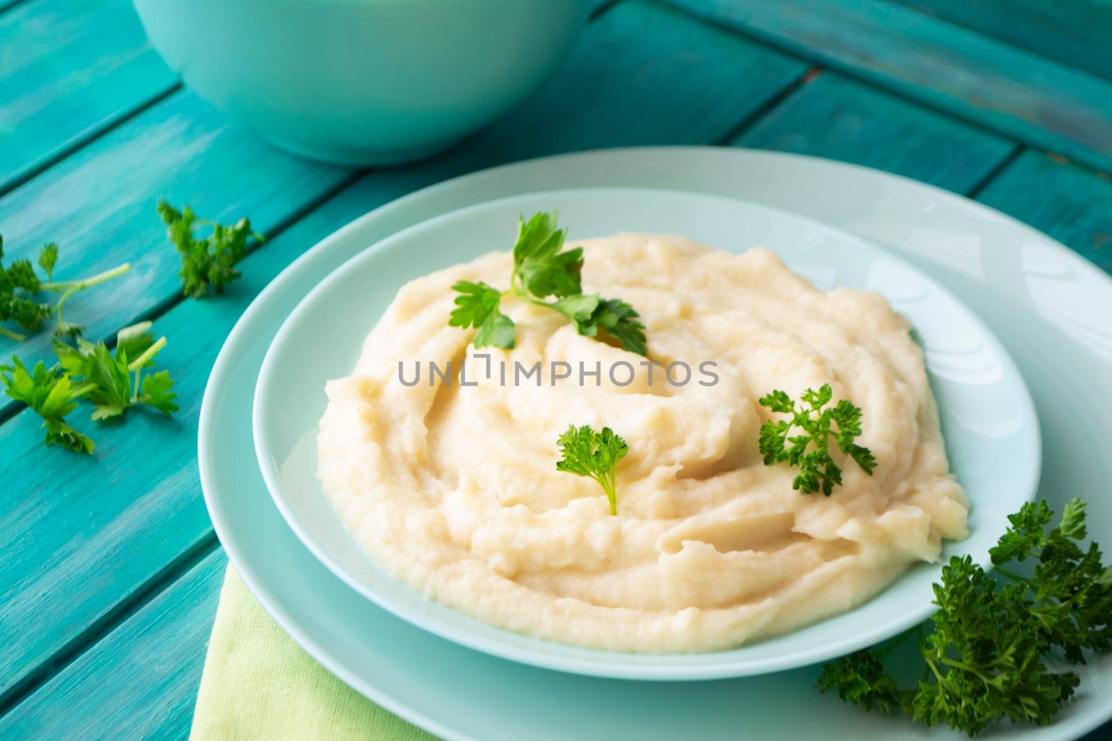 Mashed pureed potato in bowl on wooden table with persil