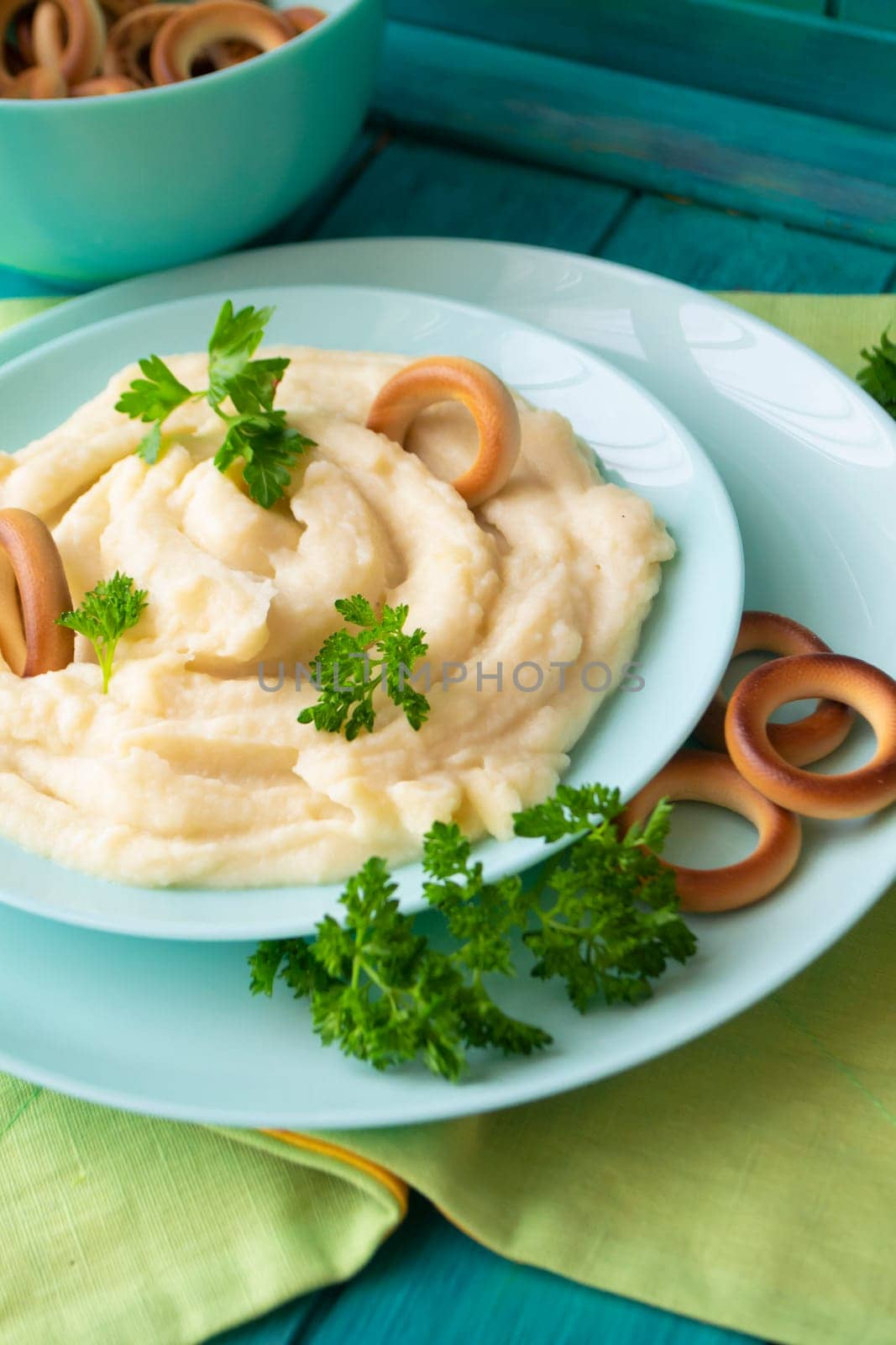 Golden mashed potatoes with parsley, decorated with bublik. Vertical image