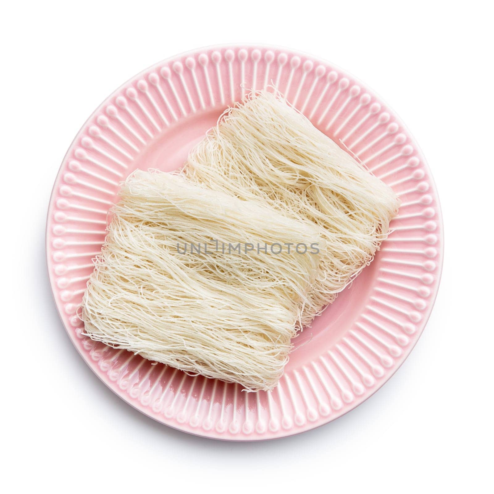 Uncooked white rice noodles on pink plate isolated on white background.