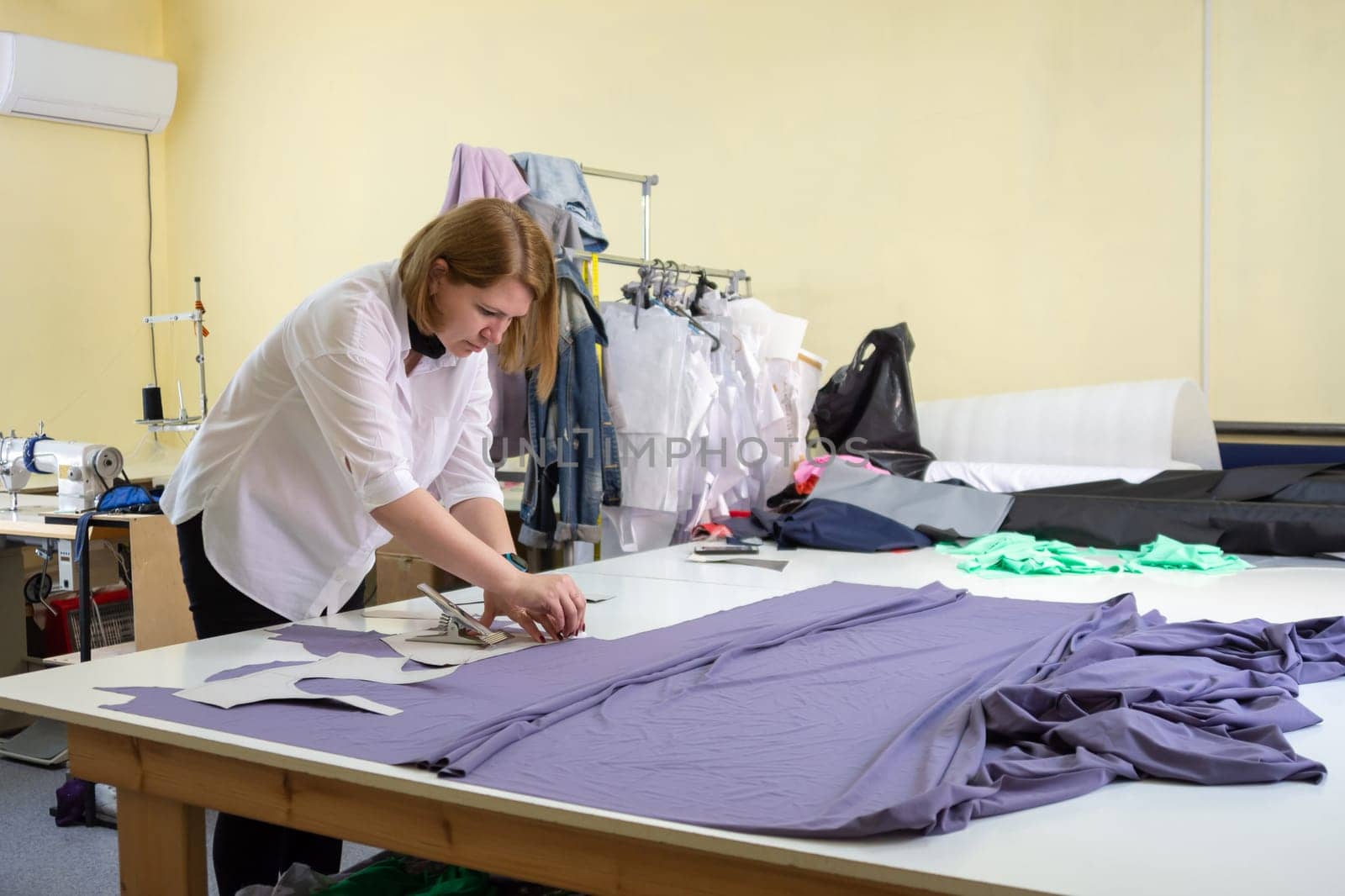 Fashion designer cuts on the material details of clothes in the workshop