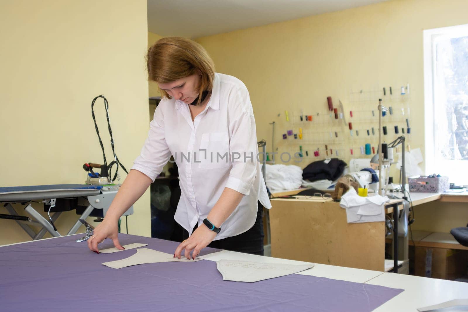 the cutter lays out the patterns on the matter on a large table in the workshop