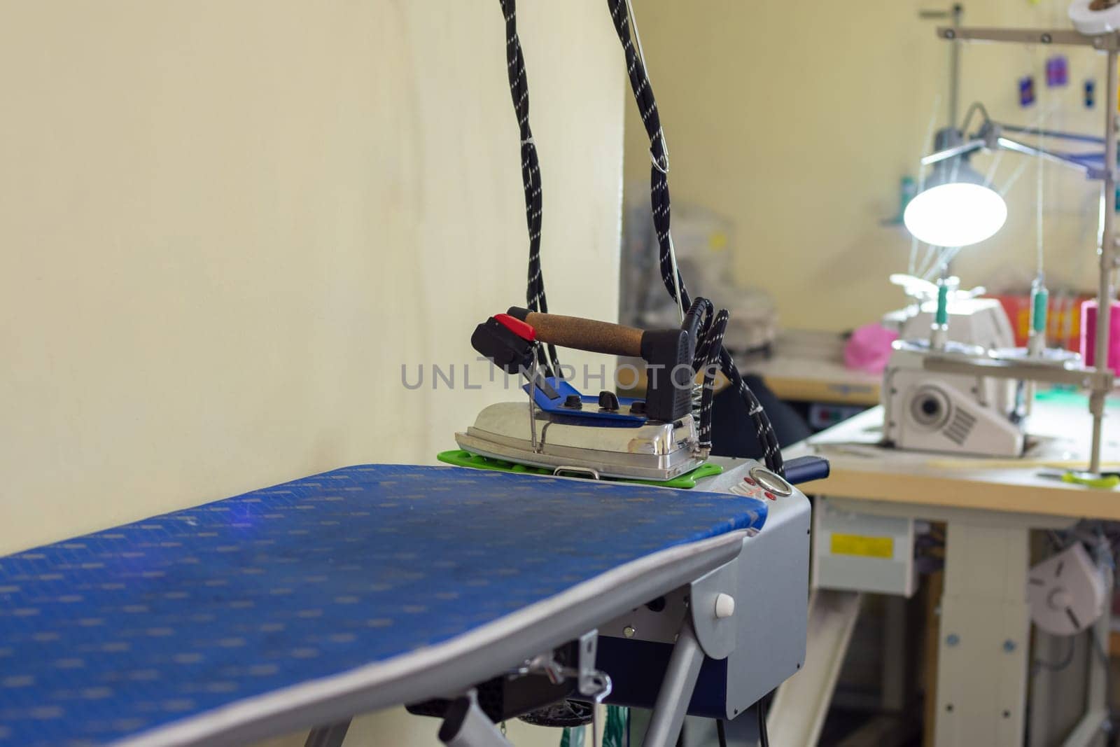 ironing machine with iron in sewing workshop