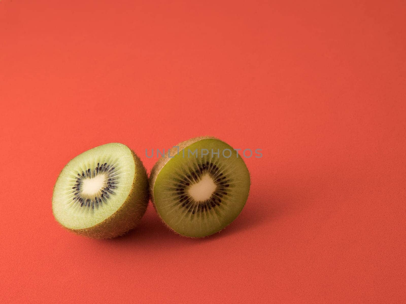 Close-up of a kiwi cut in half. Isolated on a red background.