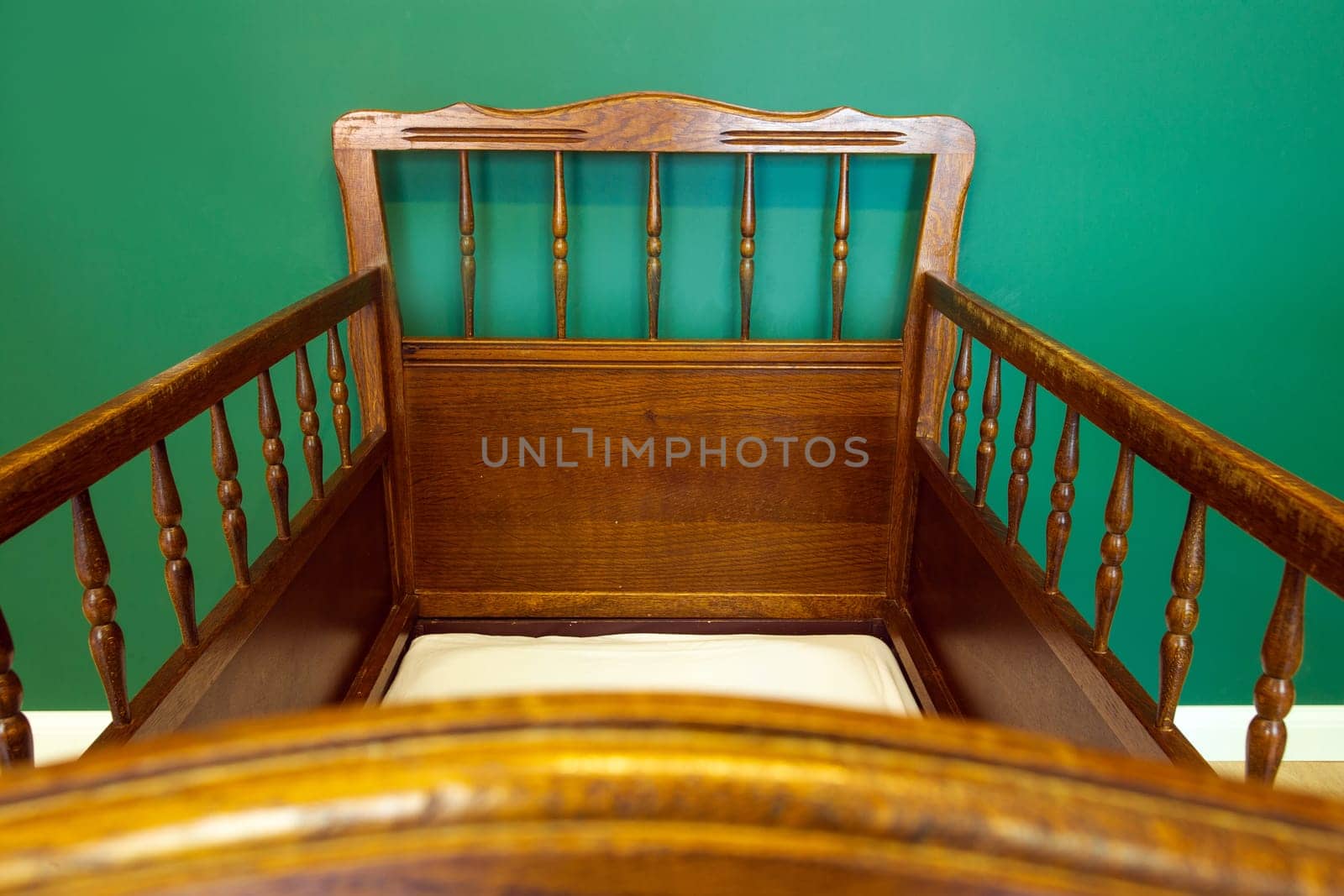 Antique retro wooden baby crib in babies room with green walls modern interior close-up