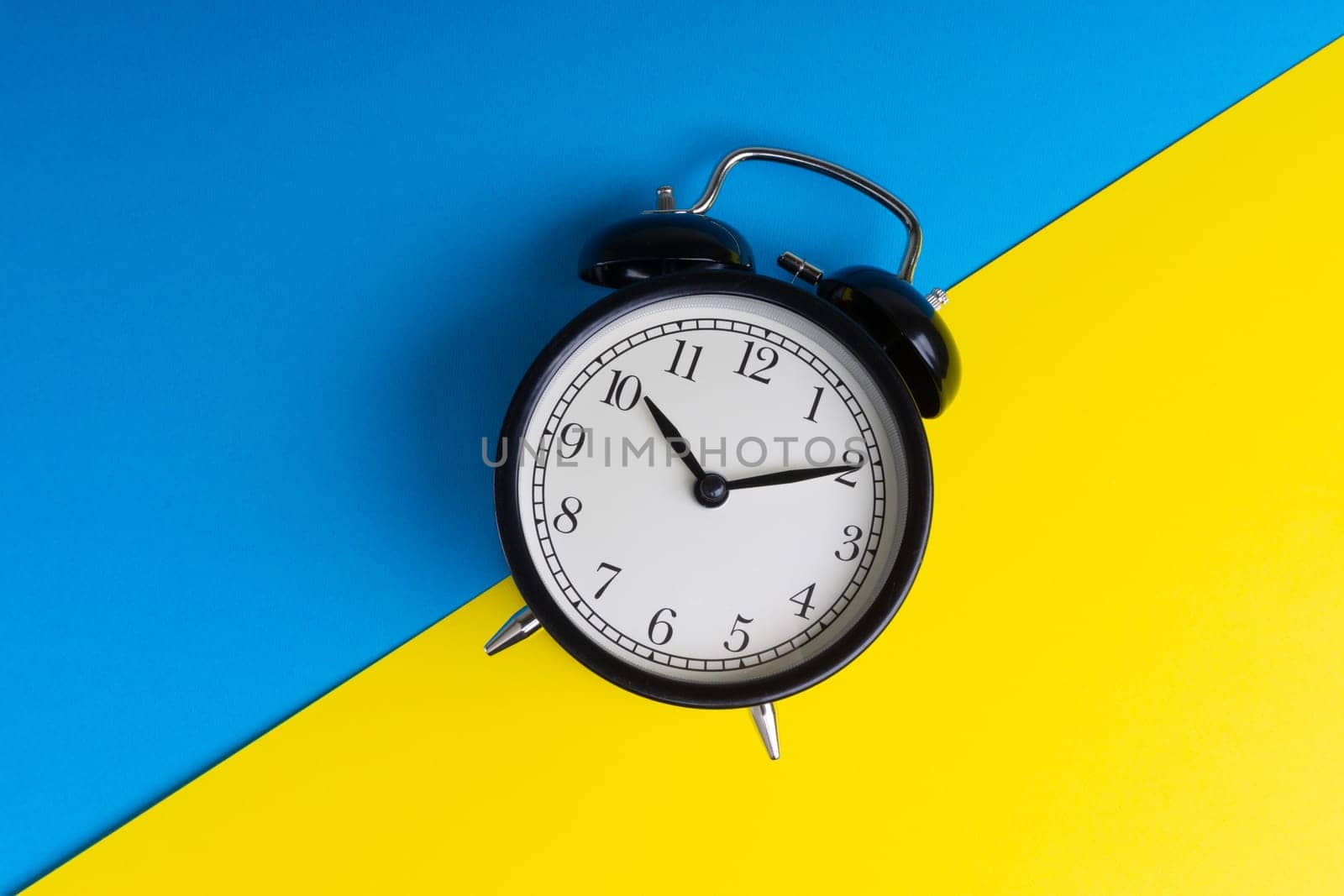 Alarm clock on a blue and yellow background. Business Concept