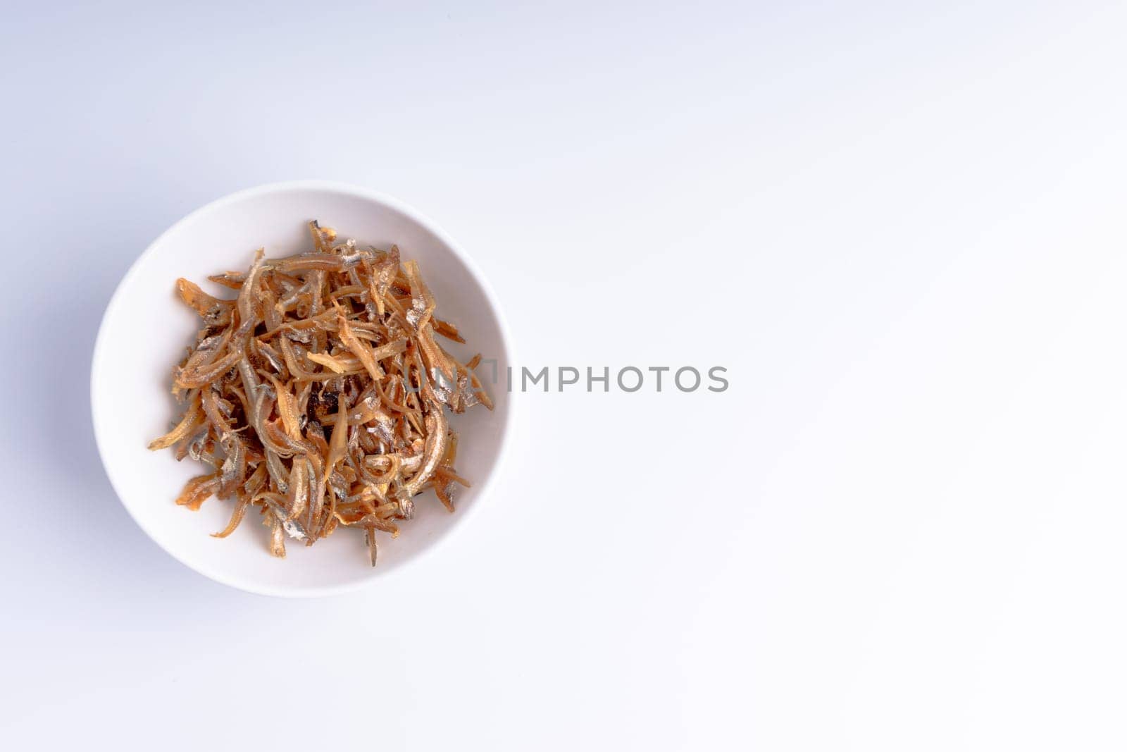 Fried anchovies in bowl close up with selective focus and crop fragment