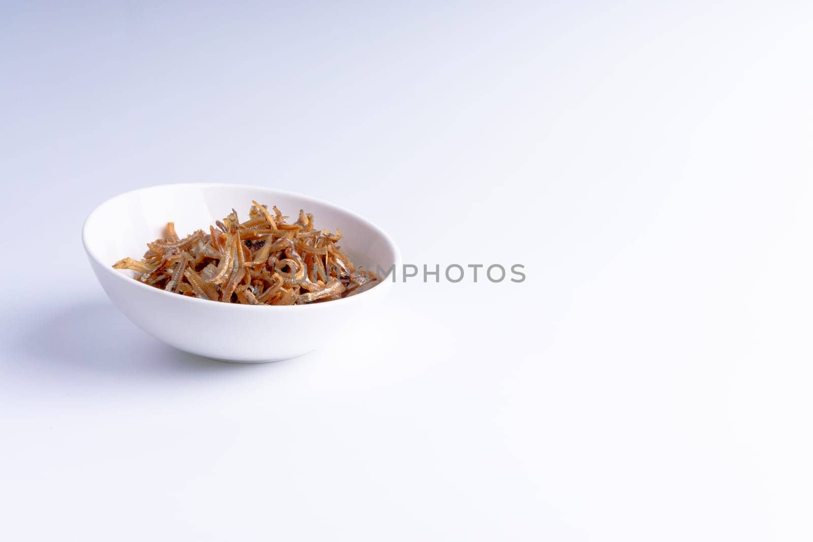 Fried anchovies in bowl close up with selective focus and crop fragment