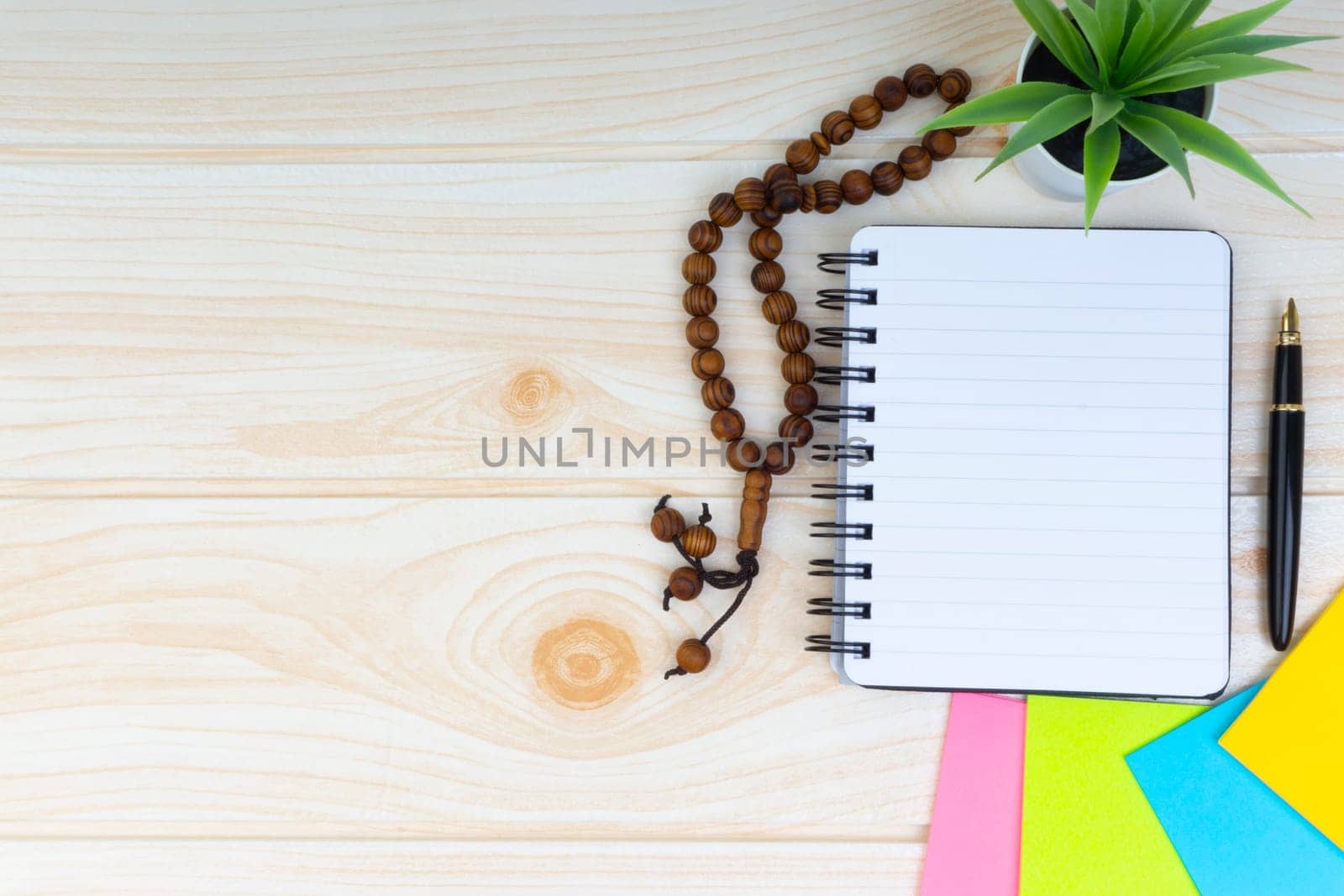 Flat lay view of workspace with Pen, spectacles, decoration flower, rosary and book.Copy Space, business and education concept.
