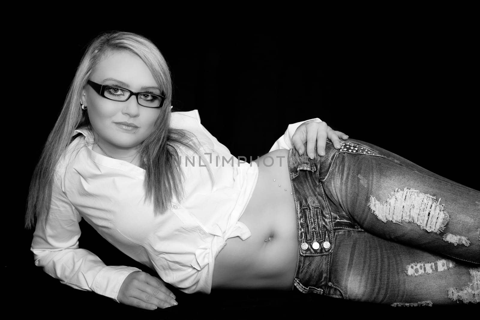 Young woman in blue jeans and a white top is lying on floor