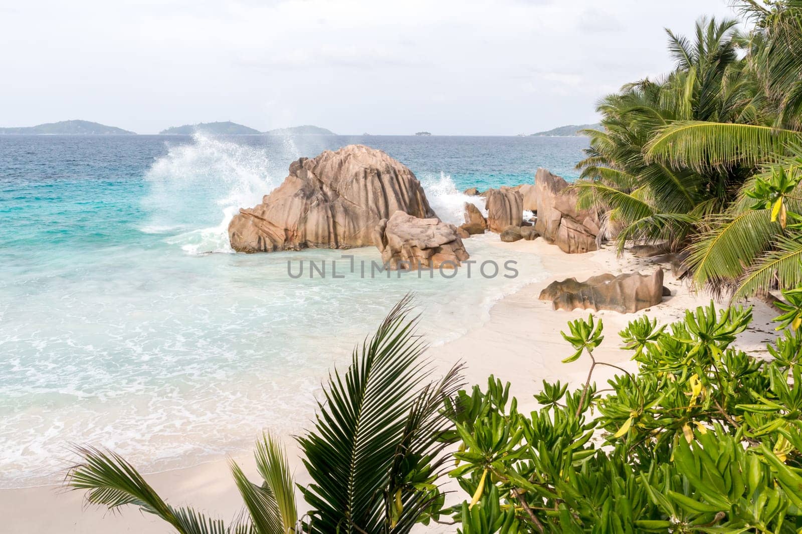 Beach with blue water and blue sky and white sand and some rocks