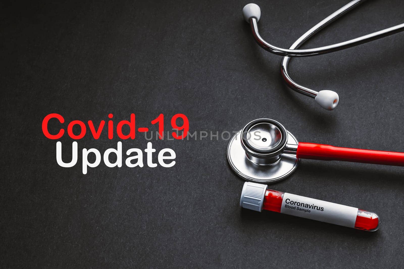COVID-19 UPDATE text with stethoscope and blood sample vacuum tube on black background. Covid or Coronavirus Concept
