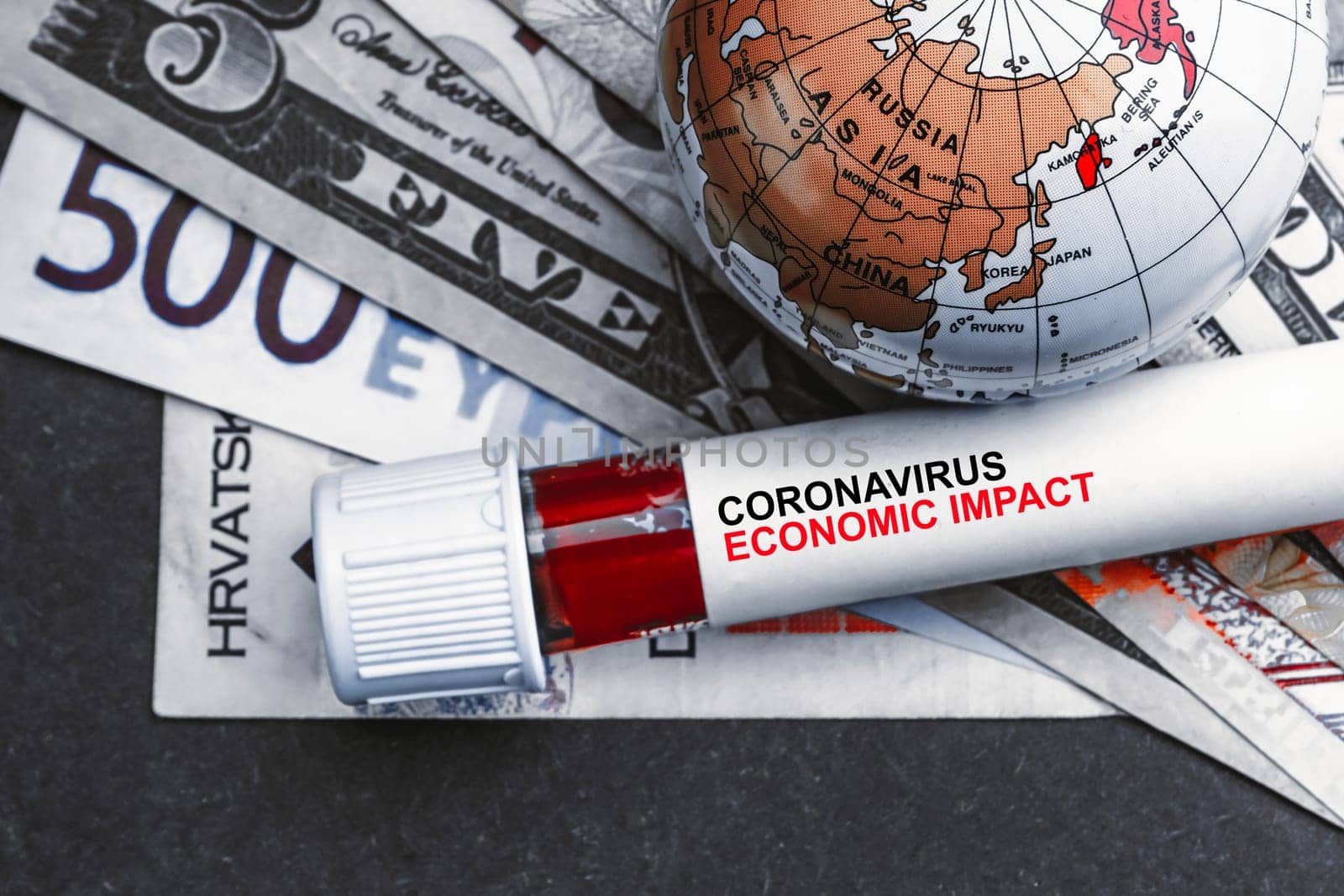 CORONAVIRUS ECONOMIC IMPACT text with currency banknotes, world globe and blood test vacuum tube on black background. Covid-19 or Coronavirus Concept