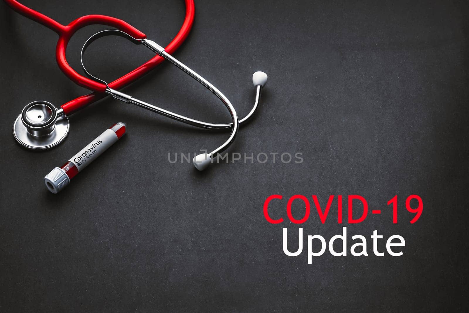 COVID-19 UPDATE text with stethoscope and blood sample vacuum tube on black background. Covid or Coronavirus Concept