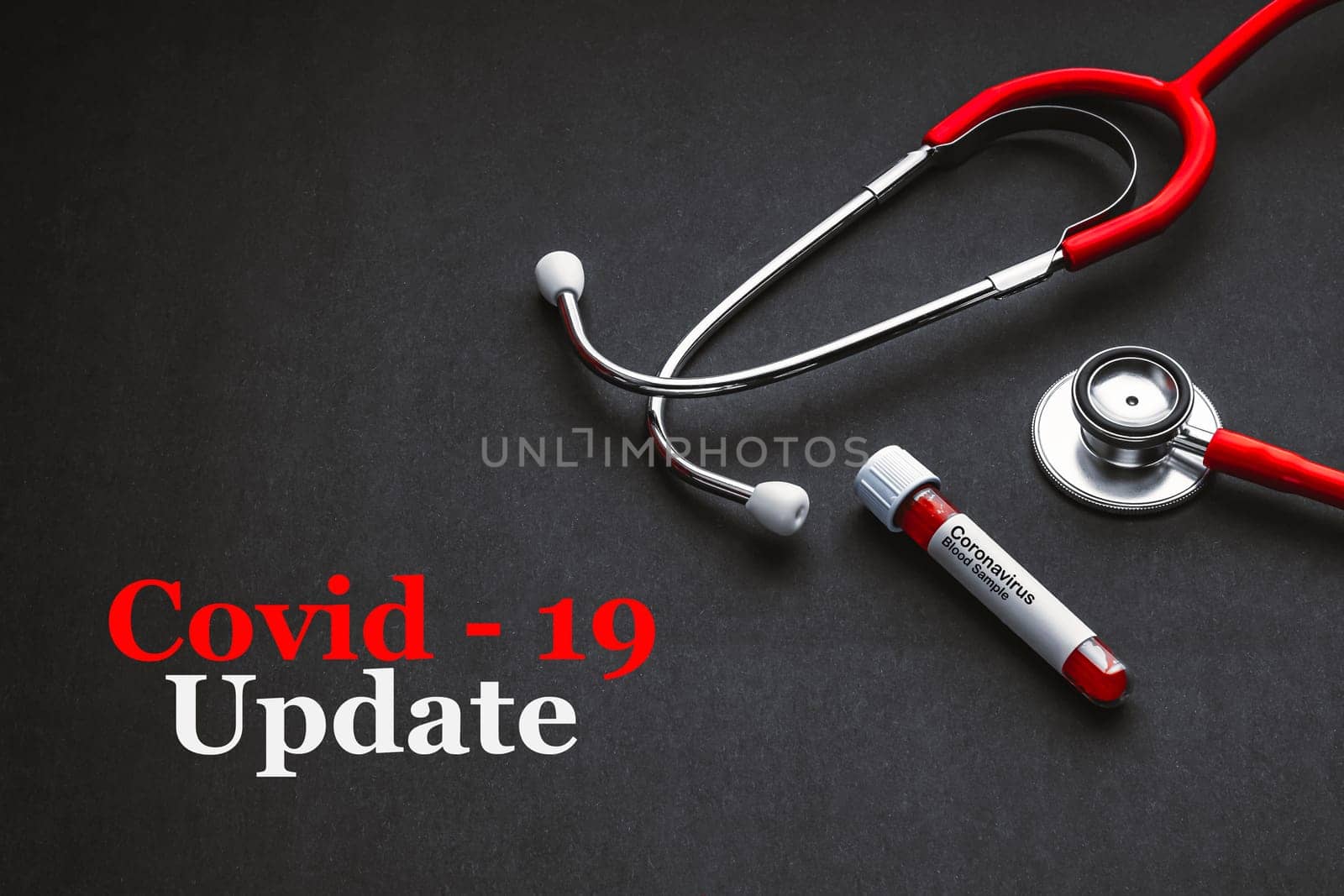 COVID-19 UPDATE text with stethoscope and blood sample vacuum tube on black background. Covid or Coronavirus Concept