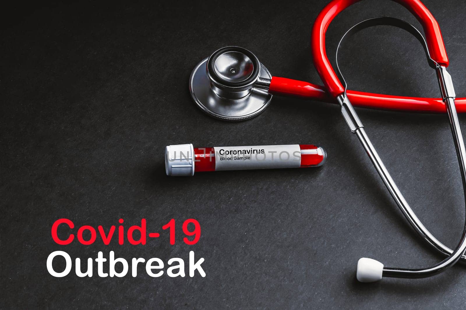 COVID-19 OUTBREAK  text with stethoscope and blood sample vacuum tube on black background. Covid or Coronavirus Concept